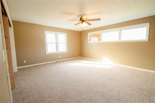 carpeted spare room featuring plenty of natural light and ceiling fan