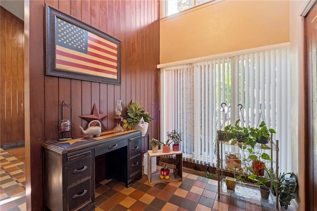 office featuring plenty of natural light, wood walls, and dark tile patterned flooring