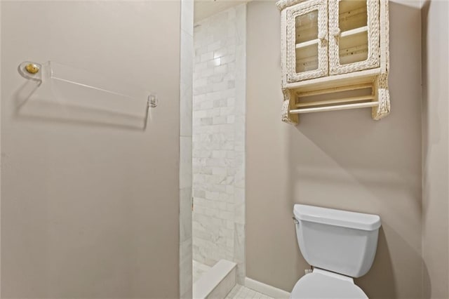 bathroom featuring tile patterned floors, toilet, and a tile shower