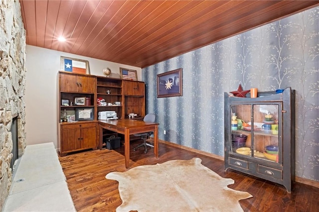 office space featuring wooden ceiling, a stone fireplace, and dark wood-type flooring