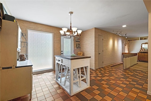 tiled dining room featuring an inviting chandelier and rail lighting