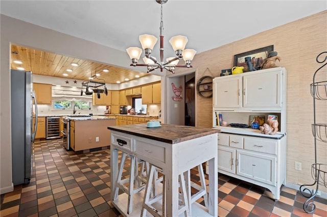 kitchen with dark tile patterned floors, stainless steel appliances, a notable chandelier, and a kitchen island