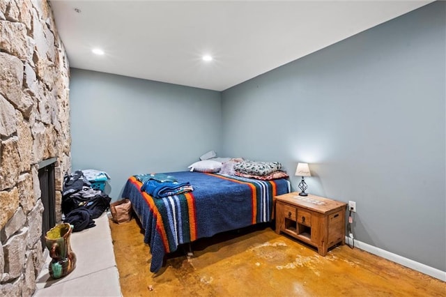 bedroom featuring a stone fireplace