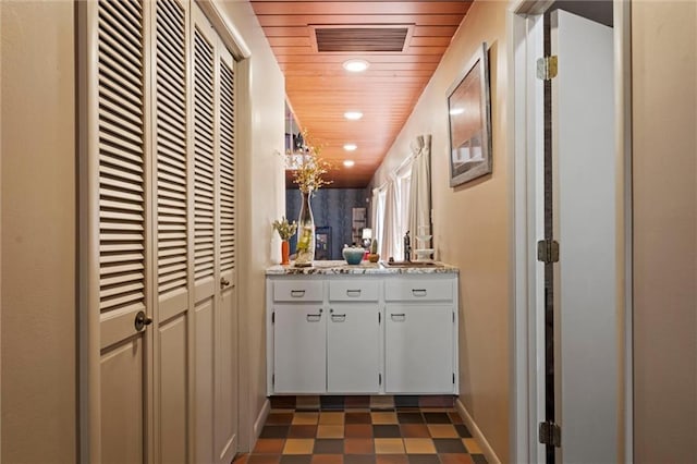 hall featuring wooden ceiling and dark tile patterned floors