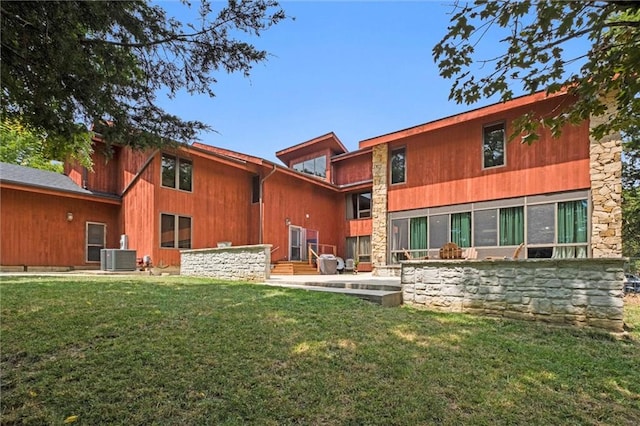 back of house featuring central AC unit and a lawn