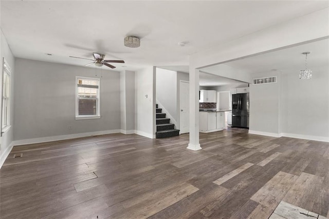 unfurnished living room with ceiling fan with notable chandelier and hardwood / wood-style floors