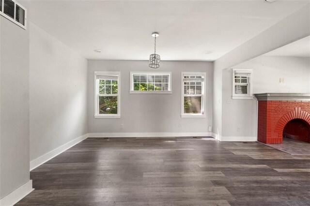 unfurnished living room featuring dark wood-type flooring and a brick fireplace