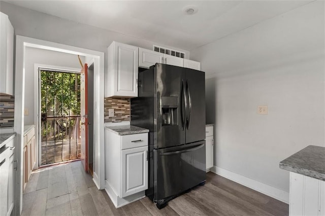 kitchen featuring decorative backsplash, hardwood / wood-style flooring, black refrigerator with ice dispenser, and white cabinetry