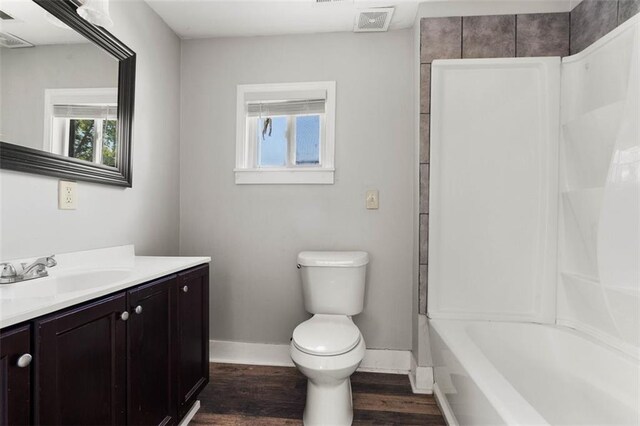 full bathroom with hardwood / wood-style flooring,  shower combination, toilet, and vanity