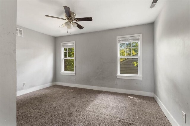 carpeted spare room featuring plenty of natural light and ceiling fan