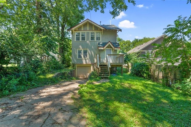 back of house featuring a garage, a yard, and a wooden deck