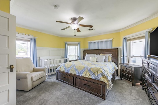 carpeted bedroom featuring ceiling fan, ornamental molding, and multiple windows