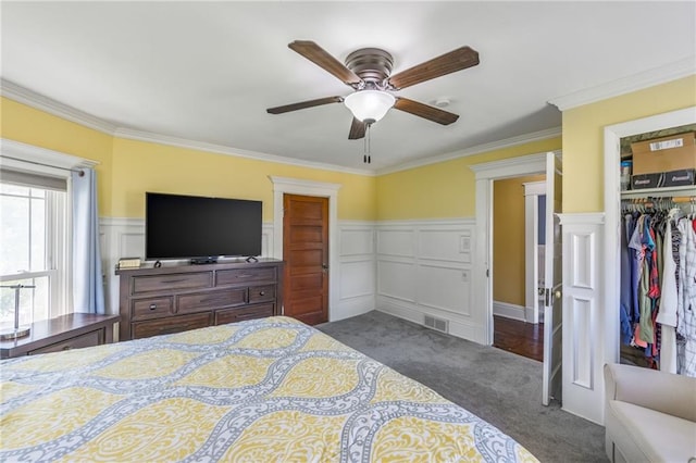 bedroom featuring ceiling fan, ornamental molding, a closet, and dark carpet