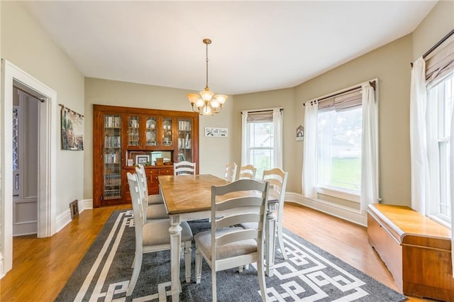 dining area with a notable chandelier and light hardwood / wood-style floors