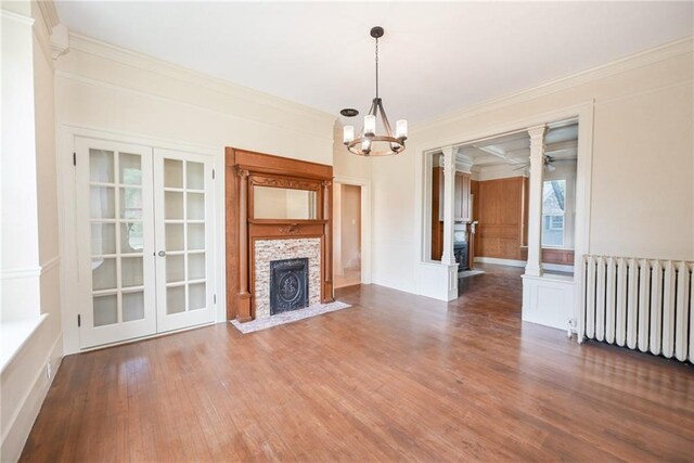 unfurnished living room with dark hardwood / wood-style floors, ornamental molding, ceiling fan with notable chandelier, and radiator