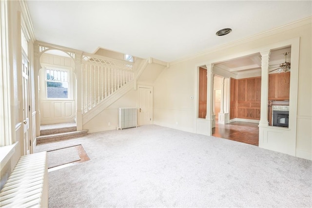 unfurnished living room with ceiling fan, crown molding, radiator, carpet floors, and decorative columns