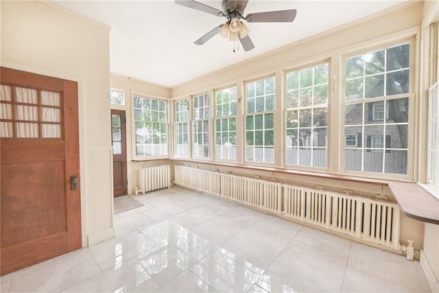 unfurnished sunroom with radiator heating unit and ceiling fan