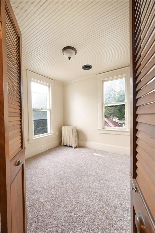 unfurnished room featuring carpet floors and radiator heating unit