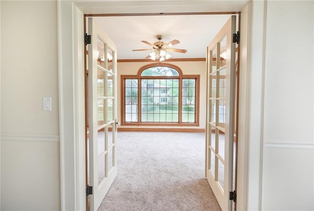 interior space with ornamental molding, light carpet, french doors, and ceiling fan