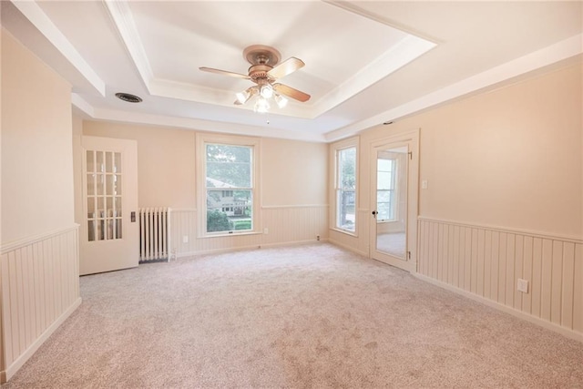 spare room featuring radiator heating unit, ceiling fan, a raised ceiling, and light colored carpet