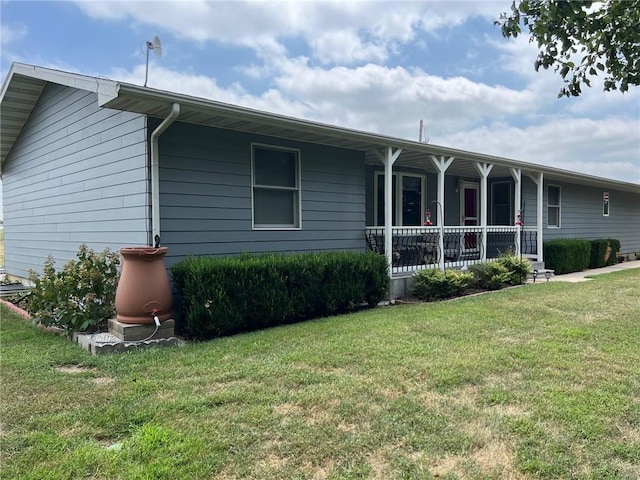 rear view of house featuring covered porch and a lawn