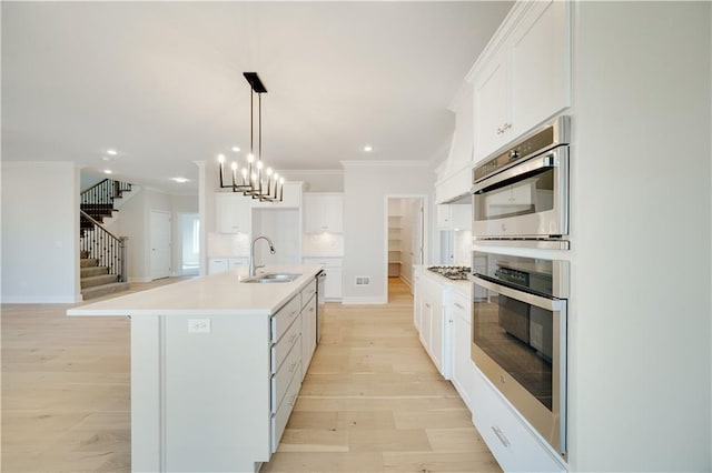 7004 NE 102nd Ct, Kansas City, MO 64156 - kitchen with ornamental molding, white cabinetry, light countertops, pendant lighting, and an island with sink