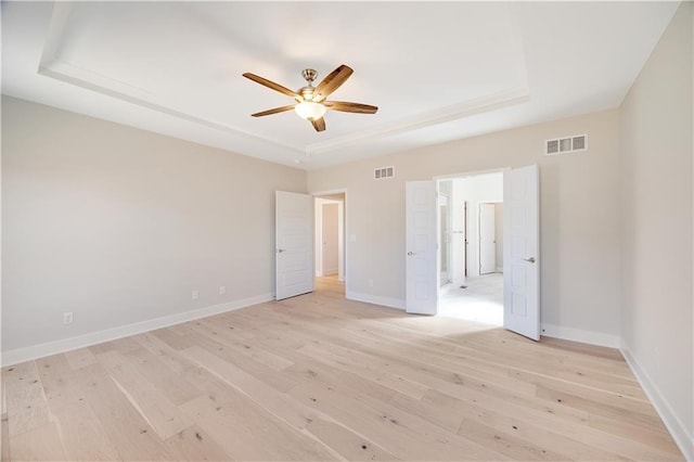7004 NE 102nd Ct, Kansas City, MO 64156 - unfurnished bedroom with a raised ceiling, light wood-style flooring, and ceiling fan