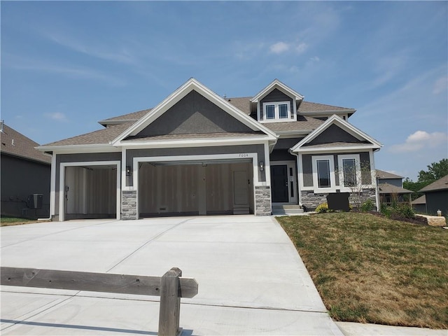 7004 NE 102nd Ct, Kansas City, MO 64156 - craftsman house with stone siding, an attached garage, driveway, a front lawn, and a shingled roof