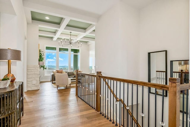 corridor featuring coffered ceiling, beam ceiling, an inviting chandelier, and light wood-type flooring