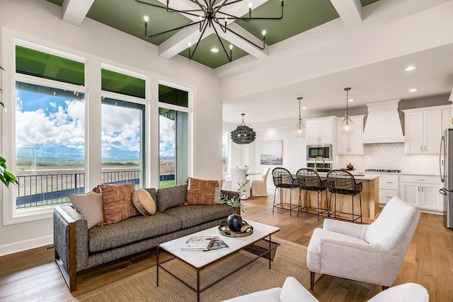 living room featuring beamed ceiling, a chandelier, light hardwood / wood-style floors, and coffered ceiling