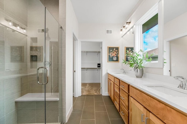 bathroom with dual vanity, a shower with door, and tile patterned flooring