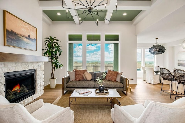 living room with a fireplace, coffered ceiling, a notable chandelier, light hardwood / wood-style floors, and beam ceiling