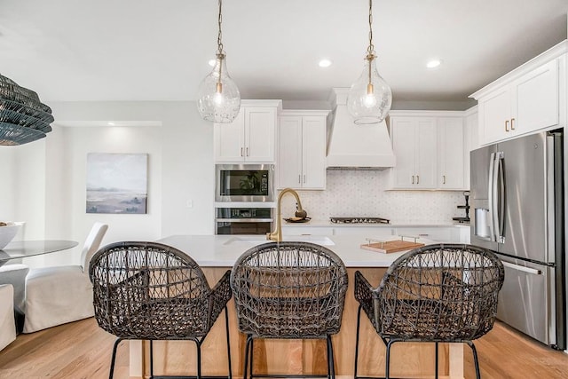 kitchen with white cabinetry, appliances with stainless steel finishes, light hardwood / wood-style floors, and custom exhaust hood