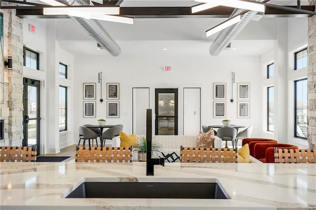 kitchen with light stone counters, a towering ceiling, and a wealth of natural light