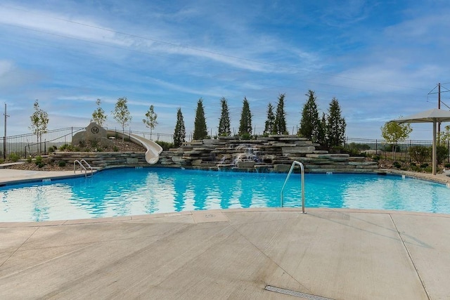 view of swimming pool featuring pool water feature, a water slide, and a patio area