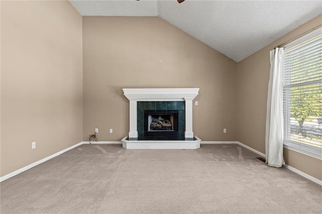 unfurnished living room with a tile fireplace, light carpet, plenty of natural light, and lofted ceiling