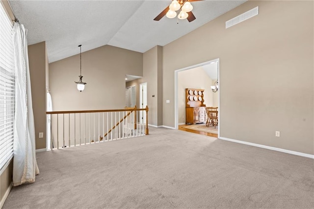 unfurnished room featuring plenty of natural light, carpet, and high vaulted ceiling