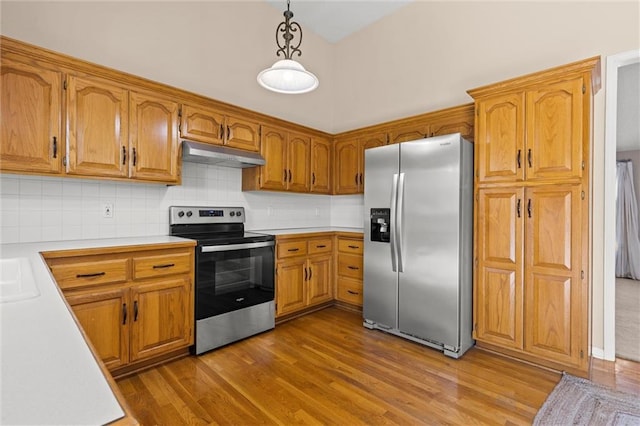 kitchen featuring backsplash, stainless steel appliances, sink, light hardwood / wood-style flooring, and hanging light fixtures