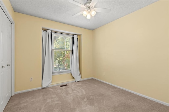 carpeted empty room with ceiling fan and a textured ceiling