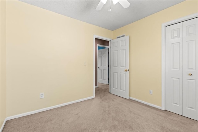 unfurnished bedroom featuring ceiling fan, light colored carpet, and a closet