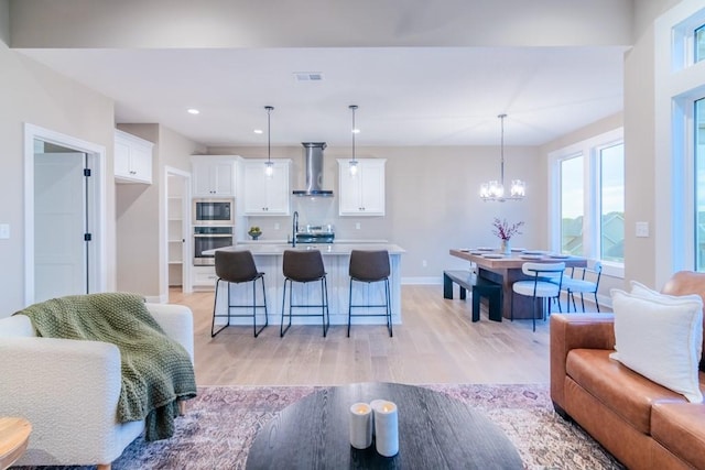 living room featuring light hardwood / wood-style floors, an inviting chandelier, and sink