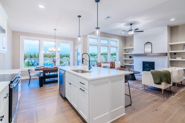 kitchen with an island with sink, sink, electric range, and white cabinetry