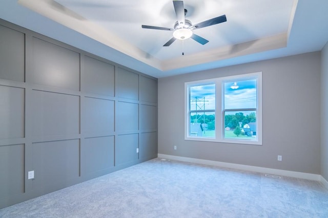 unfurnished bedroom featuring light colored carpet, ceiling fan, and a raised ceiling