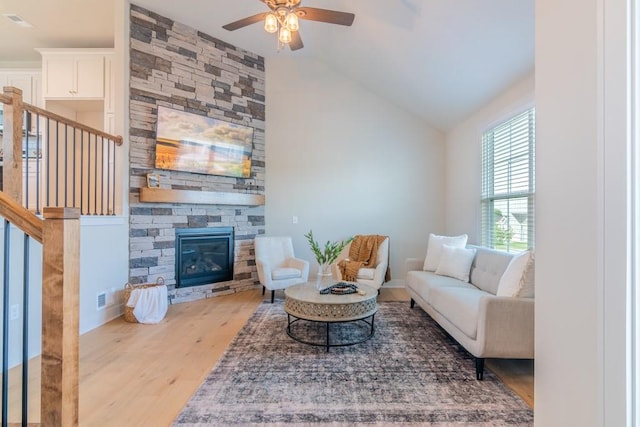 living room featuring a fireplace, light hardwood / wood-style floors, vaulted ceiling, and ceiling fan