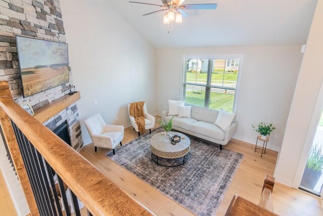 living room featuring lofted ceiling, ceiling fan, wood-type flooring, and a fireplace