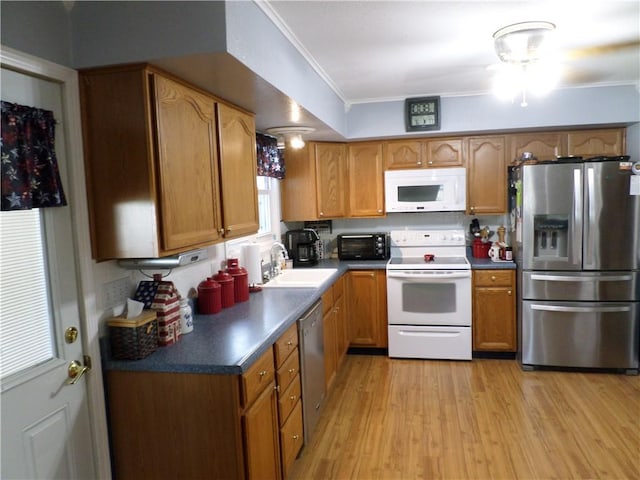 kitchen with light wood-type flooring, stainless steel appliances, sink, and ornamental molding