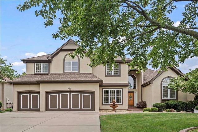 traditional-style house featuring a garage, driveway, a front lawn, and stucco siding