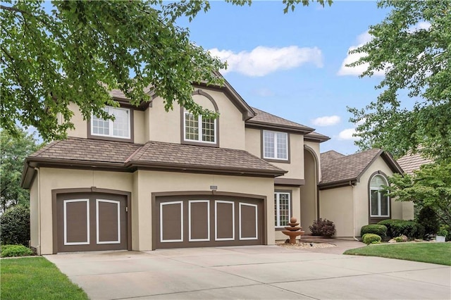 traditional home featuring driveway, an attached garage, and stucco siding