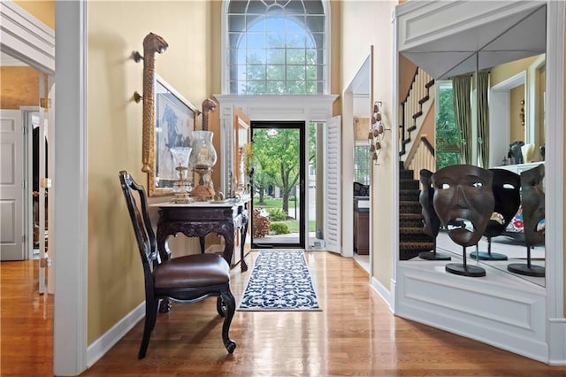 entryway featuring a high ceiling, stairway, wood finished floors, and baseboards