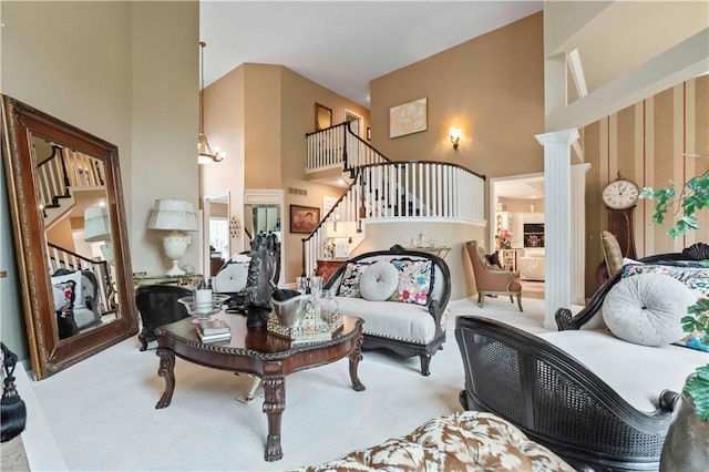 carpeted living area with decorative columns, a high ceiling, and stairs